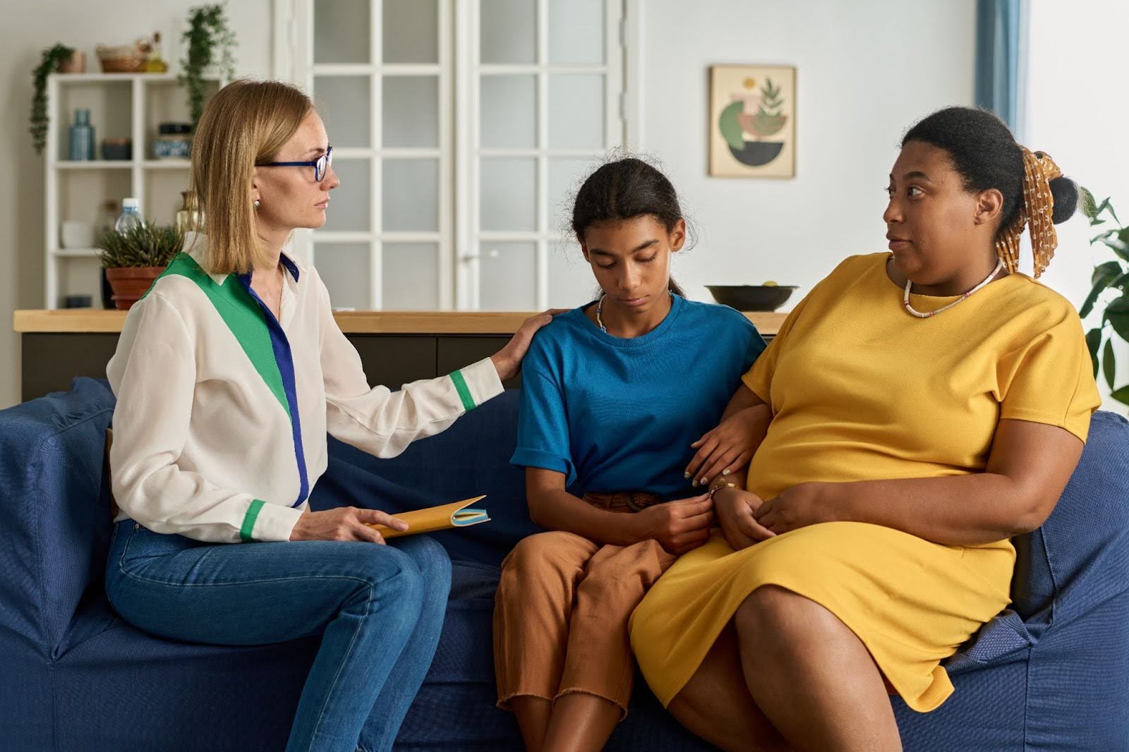 A psychologist discussing counseling for teens with a mother as the teen girl in their midst listens.