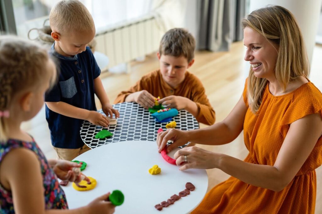 Woman leading a play therapy session with three young children.