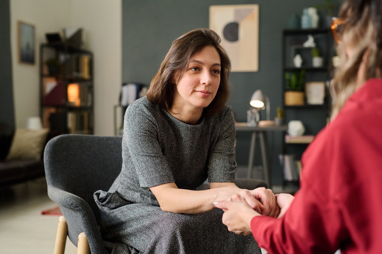 Individual therapy session with a female therapist holding a client’s hands for emotional support.