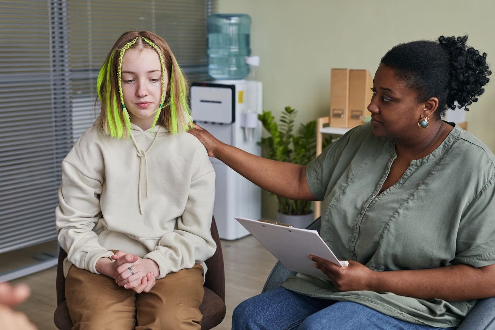 A girl with green and blonde hair undergoes adolescent therapy.