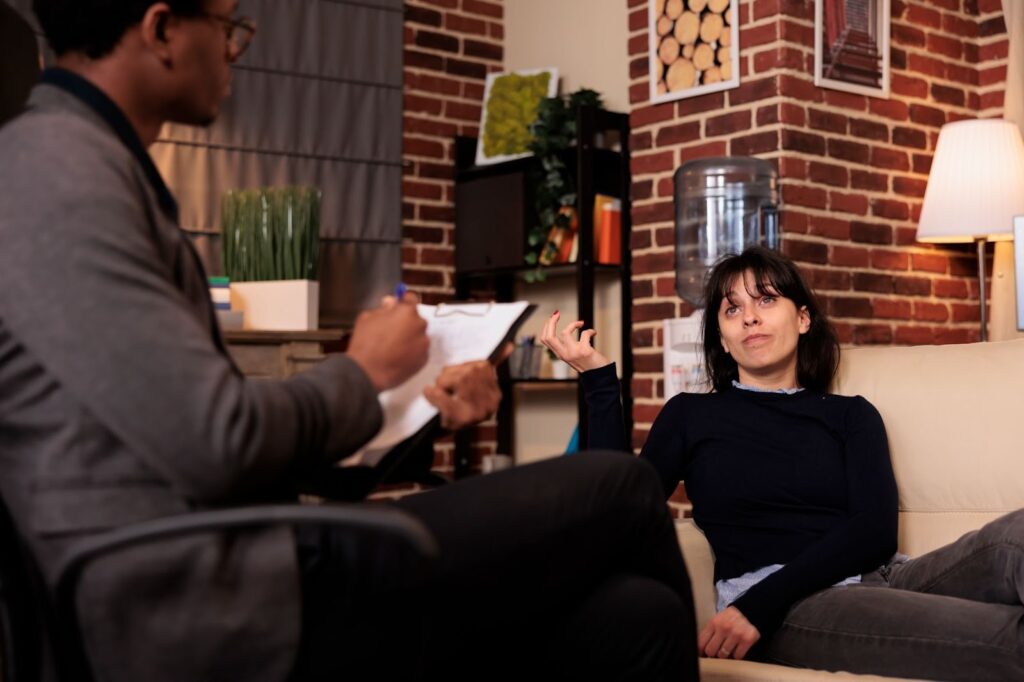 A woman lies on a couch talking to her therapist during depression counseling.